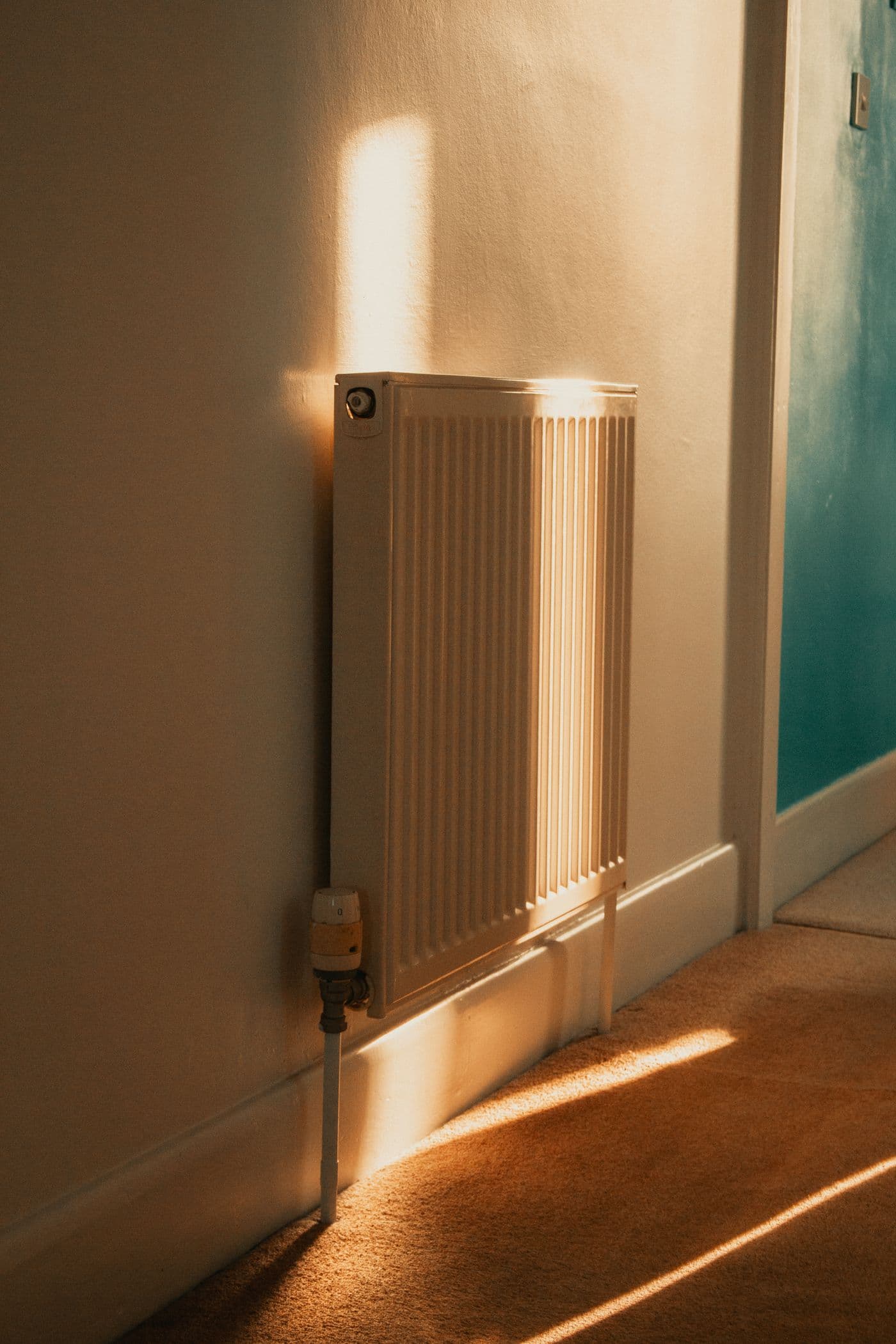 Hvid radiator oplyst af varmt aftenlys i en gang